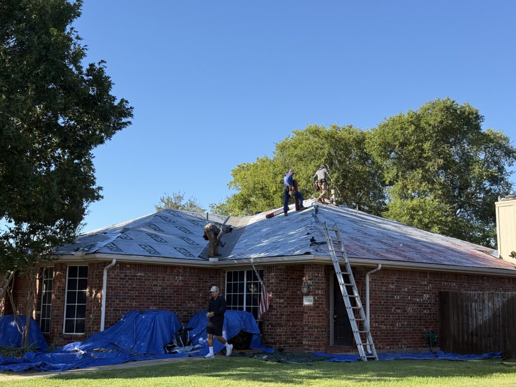 Roofing crew installing underlayment on a residential roof