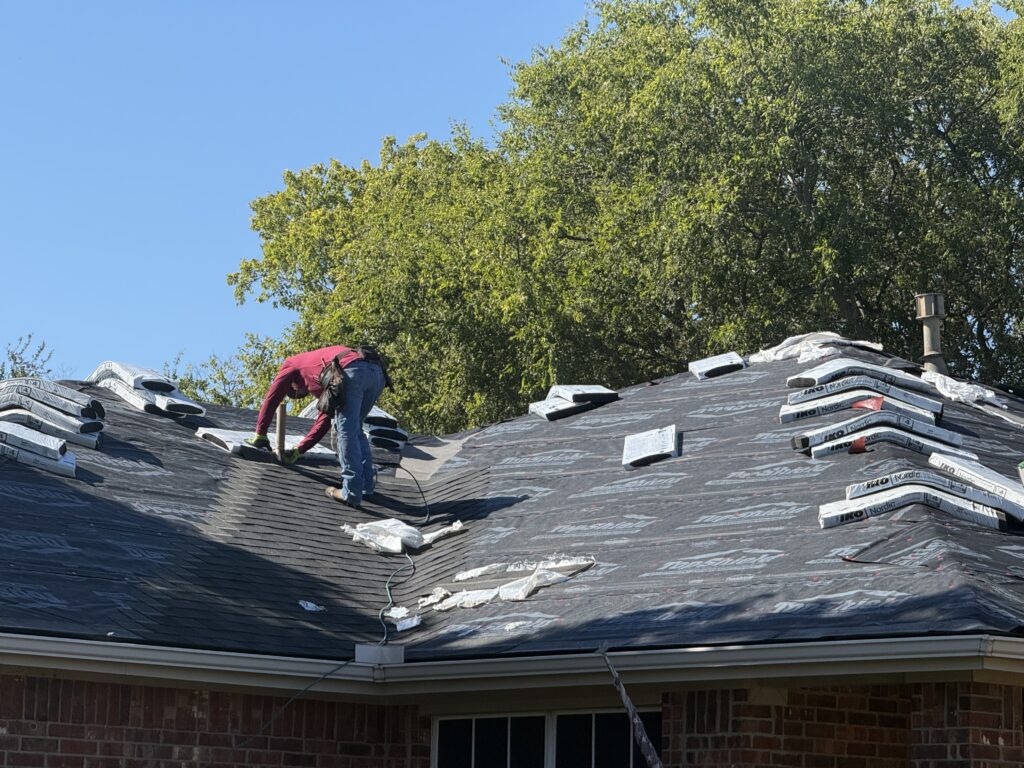 Roofer installing asphalt shingles over prepared roof underlayment
