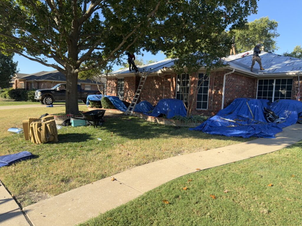 Residential roof replacement in progress with protective tarps around the home